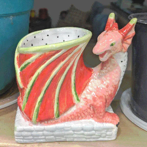painted pottery of a pencil holder shaped like a dragon, painted hot pink and lime green on the outside and white with little black dots on the inside
